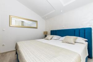 a bedroom with a large bed with a blue headboard at Apartments Prestige in Kaštela