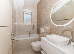 W łazience znajduje się umywalka, toaleta i lustro. w obiekcie Apartments Prestige w mieście Kaštela
