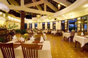 Ocean Star Resort في موي ني: مطعم بطاولات بيضاء وكراسي وطاولات وحارق طاولات