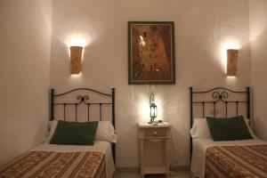 2 camas en una habitación con 2 lámparas y una mesa en Pension el Portillo, en Córdoba