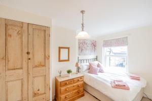 a bedroom with a bed with a wooden dresser and a window at Strayside Cottage Harrogate - cosy dog friendly cottage sleeps 4. 5 mins walk to hospital and 15 mins walk to town centre in Harrogate