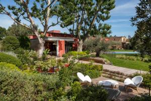a garden with white chairs and trees and a building at Best Western Plus Le Lavarin in Avignon