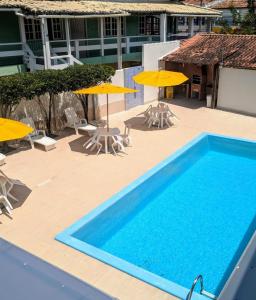 una piscina con sillas y sombrillas junto a un edificio en Hotel Capuchins, en Porto Seguro