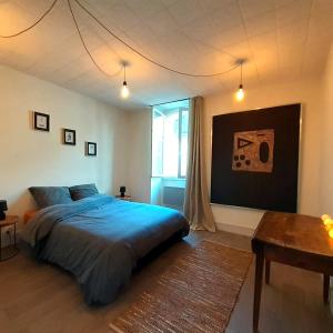 1 dormitorio con cama, mesa y ventana en Gîte "La Cachette Bourgueilloise", en Bourgueil