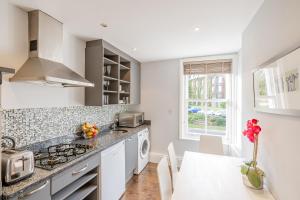a white kitchen with a stove and a sink at Upper Swan View Apartment in Harrogate