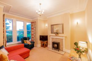 a living room with a red couch and a fireplace at Harlow View Apartment, Harrogate - 2 bedroom duplex apartment. Sleeps 6. Dog Friendly. in Harrogate