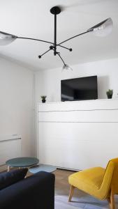 sala de estar con silla amarilla y TV en Céleste - Hypercentre parking privé, en Poitiers