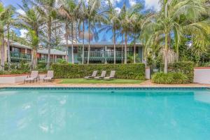 a swimming pool in front of a house with palm trees at Byron Getaway @the Crest in Byron Bay