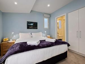 a bedroom with a large bed with purple sheets at Stonehill Villa - 3 Bed in Queenstown