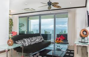 sala de estar con sofá negro y ventana grande en Best in Jaco Condos at Diamante del Sol, en Jacó