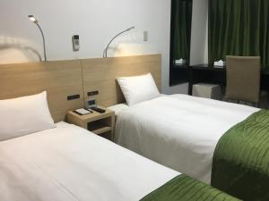 een hotelkamer met 2 bedden en een bureau bij High Set HOTEL SHIZUOKA Inter in Shizuoka