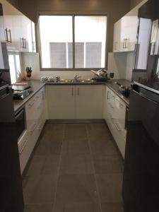 a kitchen with white cabinets and a large window at The Cozy Hostel - Motel in Darwin