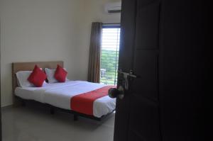 a bedroom with a bed with red pillows and a window at Hotel Relax Inn in Nagpur