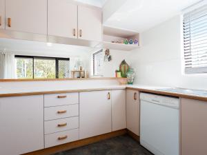 a kitchen with white cabinets and a dishwasher at Carindale 13 large ground floor unit with pool and tennis court in Nelson Bay