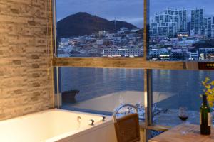 a bath tub in a kitchen with a view of the city at Lium Spa Hostel in Yeosu