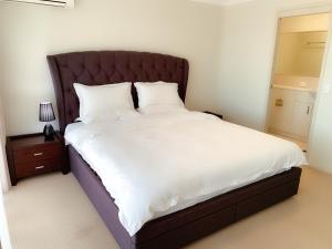 a bedroom with a large bed with white sheets at Forest Lake best stay in Wacol +8 photos