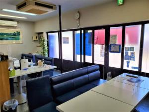 una sala de espera con sillas, mesas y ventanas en Yado Seven Beach, en Naoshima