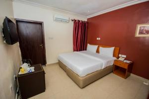 um quarto de hotel com uma cama e uma televisão em Choice Suites III em Ikeja