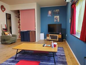 a living room with a coffee table and a tv at Mrs. Maroulla's HOUSE in Naoshima