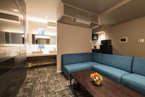 a living room with a blue couch and a table at GRAND BASE Kagoshima Tenmonkan in Kagoshima