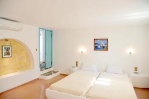 a white bedroom with a bed and a window at Medusa Beach Resort & Suites in Plaka