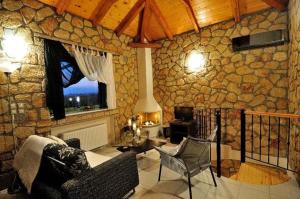 a living room with a stone wall with a couch and chairs at Messinian Horizons in Marathopolis