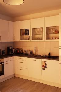 una cocina blanca con armarios y electrodomésticos blancos en Ferienwohnung in Birkenwerder mit Balkon, en Birkenwerder