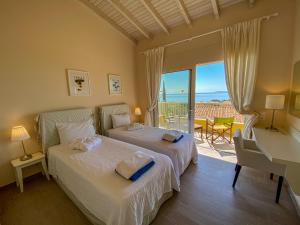 a bedroom with two beds and a desk and a balcony at La Riviera Barbati Seaside Apartments & villas in Barbati