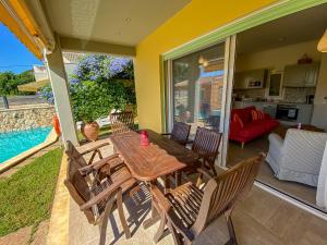 a wooden table and chairs on a patio with a pool at La Riviera Barbati Seaside Apartments & villas in Barbati