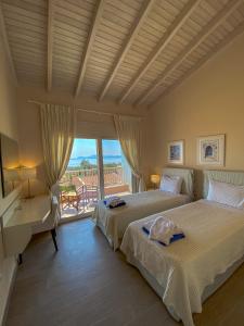 two beds in a bedroom with a view of the ocean at La Riviera Barbati Seaside Apartments & villas in Barbati