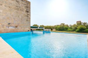 a swimming pool with blue water next to a stone wall at Possessio Sa Barrala Gallinero in Campos