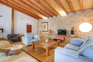 a living room filled with furniture and a stone wall at Possessio Sa Barrala Gallinero in Campos