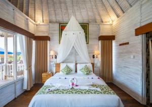 a bedroom with a white bed with a pink bow on it at Island Retreat Cottage in Nusa Lembongan