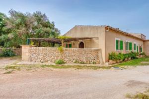 a house with a stone wall next to a building at Possessio Sa Barrala Casa del Pages in Campos