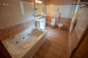 a large bathroom with a tub and a toilet at Pensiunea Sura Dacilor - Alex in Poiana Brasov
