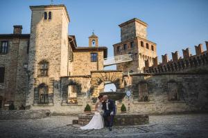 Una novia y un novio posando frente a un castillo en Hotel Castello Di Vigoleno, en Vigoleno