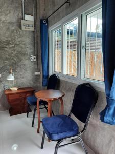 a room with two chairs and a table and two windows at Pottery Street House in Sukhothai