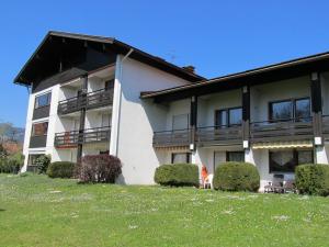 ein weißes Gebäude mit einem Balkon und einigen Büschen in der Unterkunft Ferienwohnungen Sattler in Oberstdorf