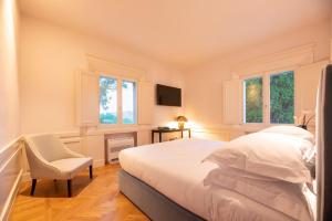 a bedroom with a bed and a chair and windows at Villa Monty Banks in Cesena