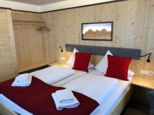 una camera con due letti con cuscini rossi e bianchi di Berghotel Türlwand a Ramsau am Dachstein