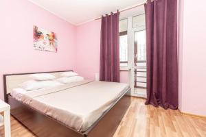 een slaapkamer met een bed met paarse gordijnen en een raam bij Abazhur Apartment Ekaterinburg Stachek in Jekaterinaburg