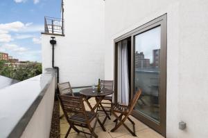 a patio with a table and chairs on a balcony at London City Apartments - Luxury and spacious apartment with balcony in London