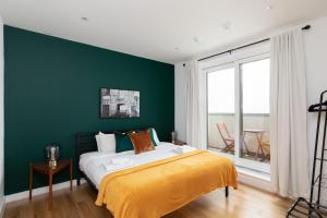 una camera da letto con pareti verdi e un letto con una coperta gialla di London City Apartments - Luxury and spacious apartment with balcony a Londra