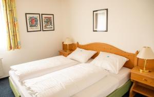 a bedroom with two white beds and two lamps at Alpenlodge Val Gronda in Obersaxen