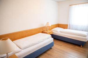 two beds in a room with a window at Alpenlodge Val Gronda in Obersaxen