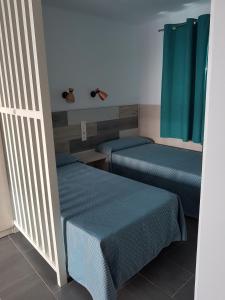 twee bedden in een kamer met blauwe lakens bij Atlantis Las Lomas in Puerto del Carmen