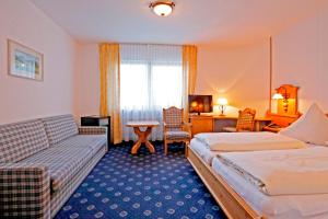 une chambre d'hôtel avec deux lits et un canapé dans l'établissement Hotel Restaurant Fronmühle, à Bad Dürkheim