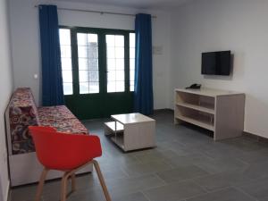 een woonkamer met een rode stoel en een televisie bij Atlantis Las Lomas in Puerto del Carmen