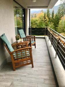 a porch with two chairs and a table on a balcony at Apartamentul Verde Silver Mountain Poiana Brașov in Poiana Brasov