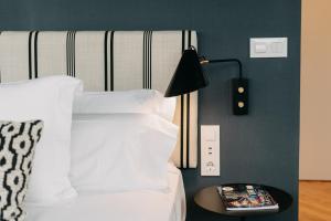 a bed with a black lamp and a book on a table at Soho Boutique Colón in Málaga